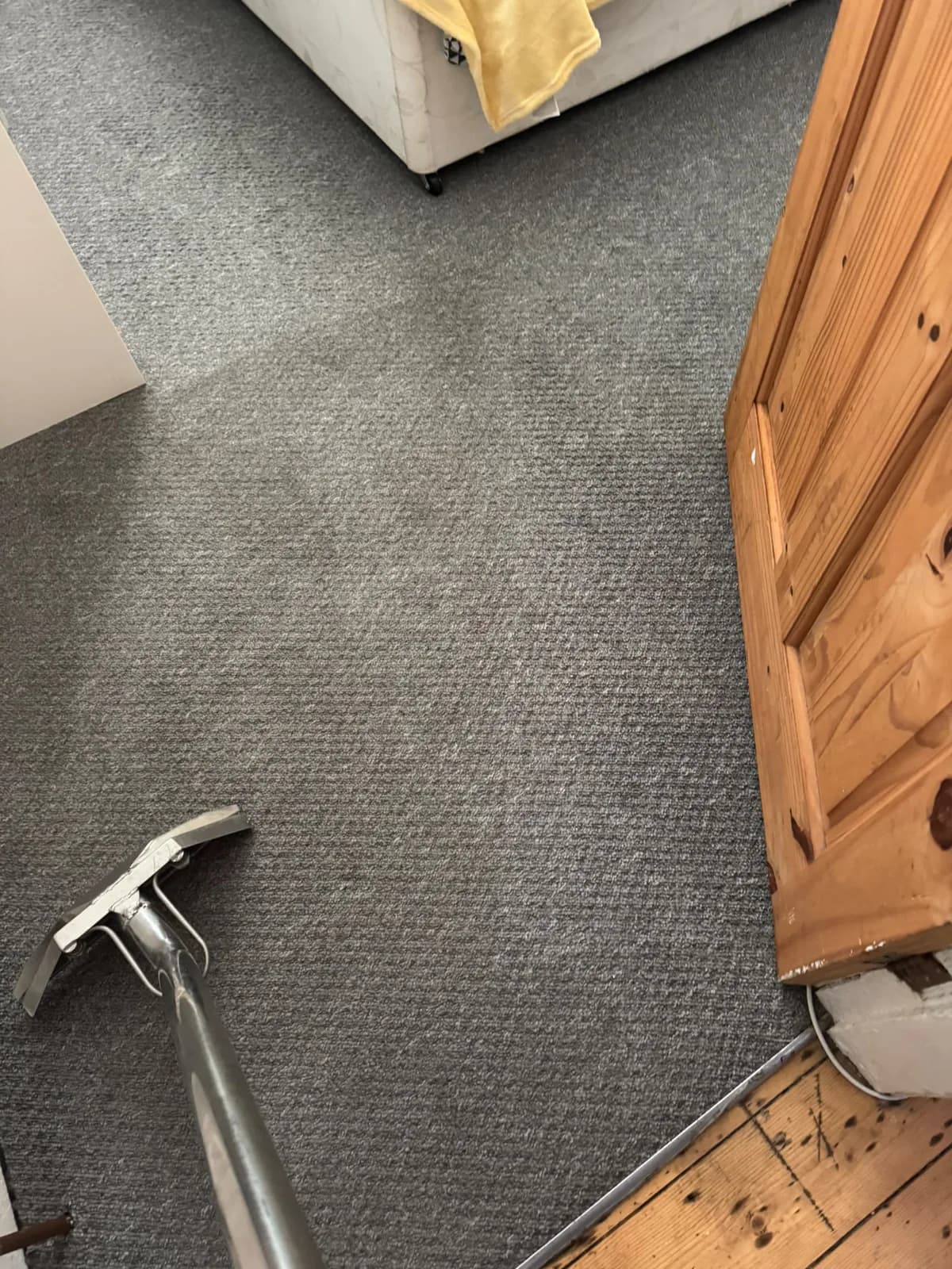 A carpet extraction wand being used on a bedroom carpet