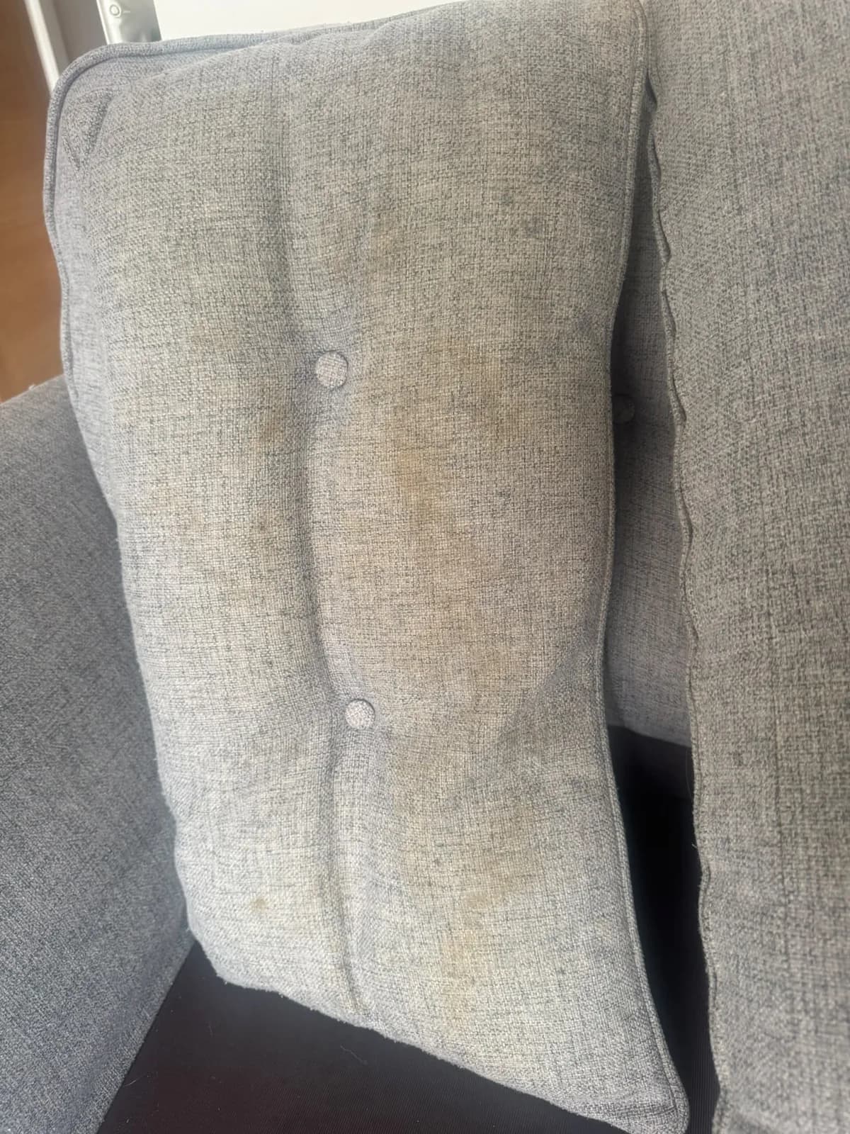 A stained grey upholstery cushion ready for cleaning